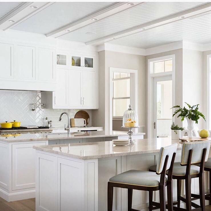 White kitchen with island, cabinets, and seating, featuring a light countertop and beige walls