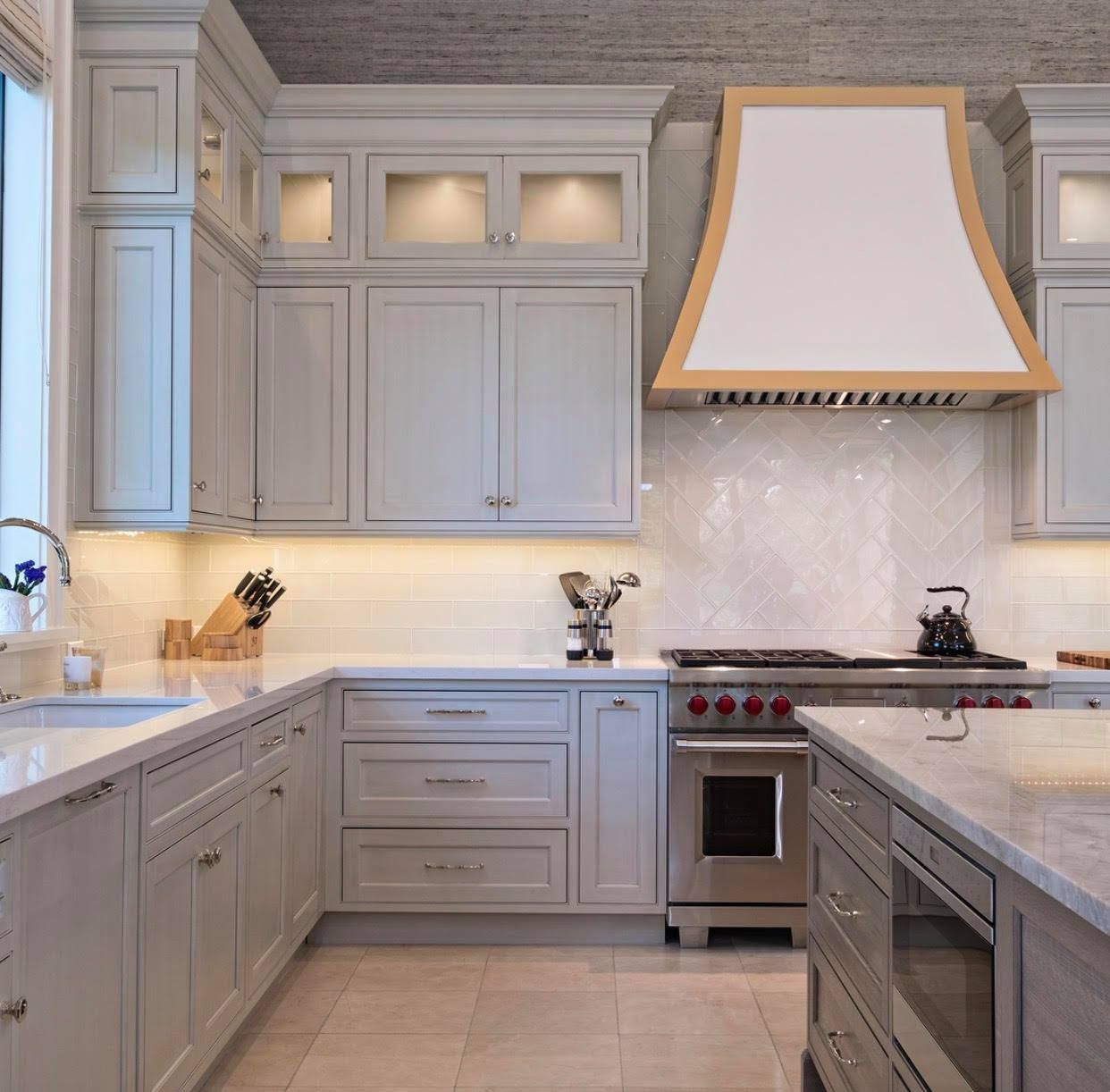 Elegant gray kitchen with white countertops, stainless steel appliances, and a wood-accented range hood
