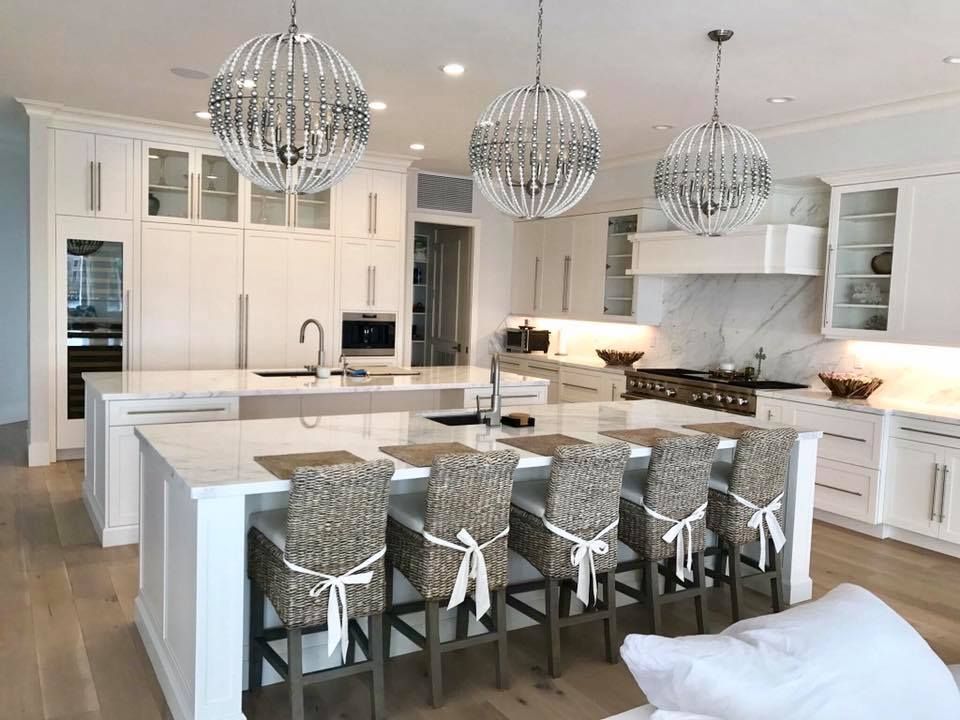 Bright white kitchen with large island, pendant lights, and wicker bar stools