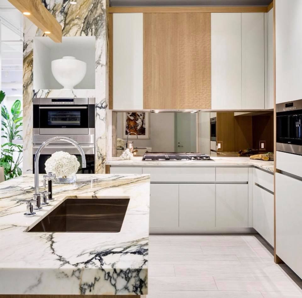 Modern kitchen with marble countertops, white cabinets, and wood accents