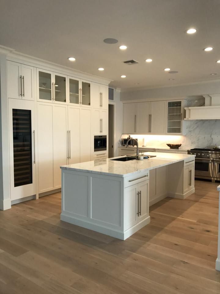 White kitchen with island, cabinets, wine cooler, and hardwood floors