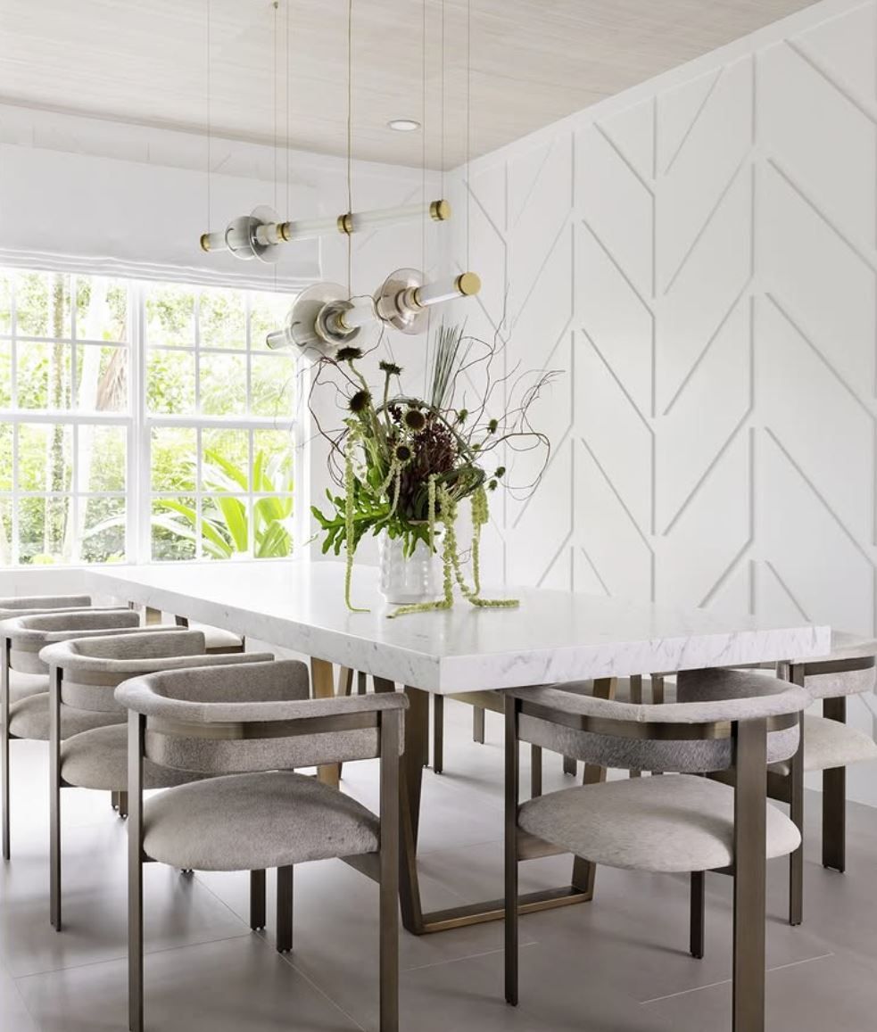 Elegant dining room with marble table, grey chairs, and patterned white wall
