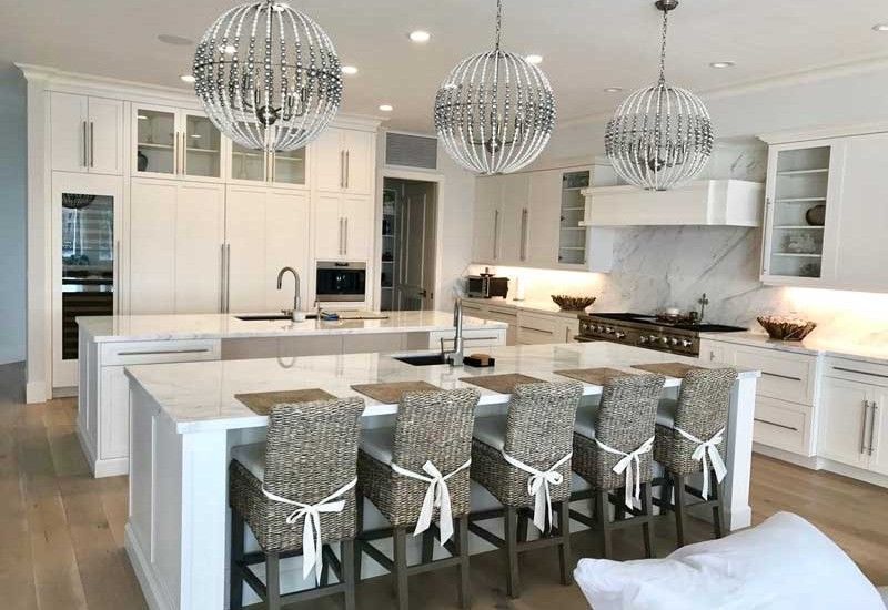 Bright white modern kitchen with an island, stools, and orb pendant lights