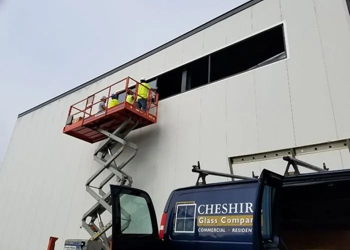 Two workers in a red scissor lift inspecting a building’s upper window opening