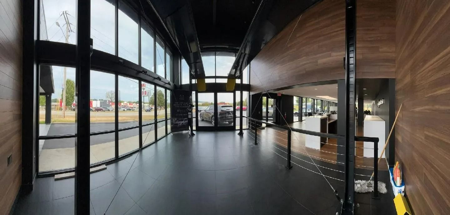 Empty modern interior with glass walls, dark floors, and wood-paneled ceiling, viewed down a corridor
