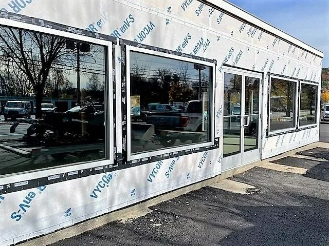 Exterior of a vacant storefront with large windows and protective wrap around the building
