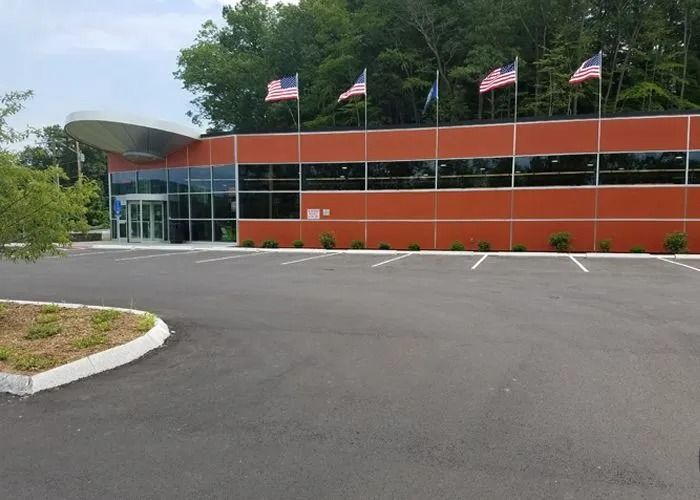 Modern building with orange facade, glass entrance, and flags flying along the roofline