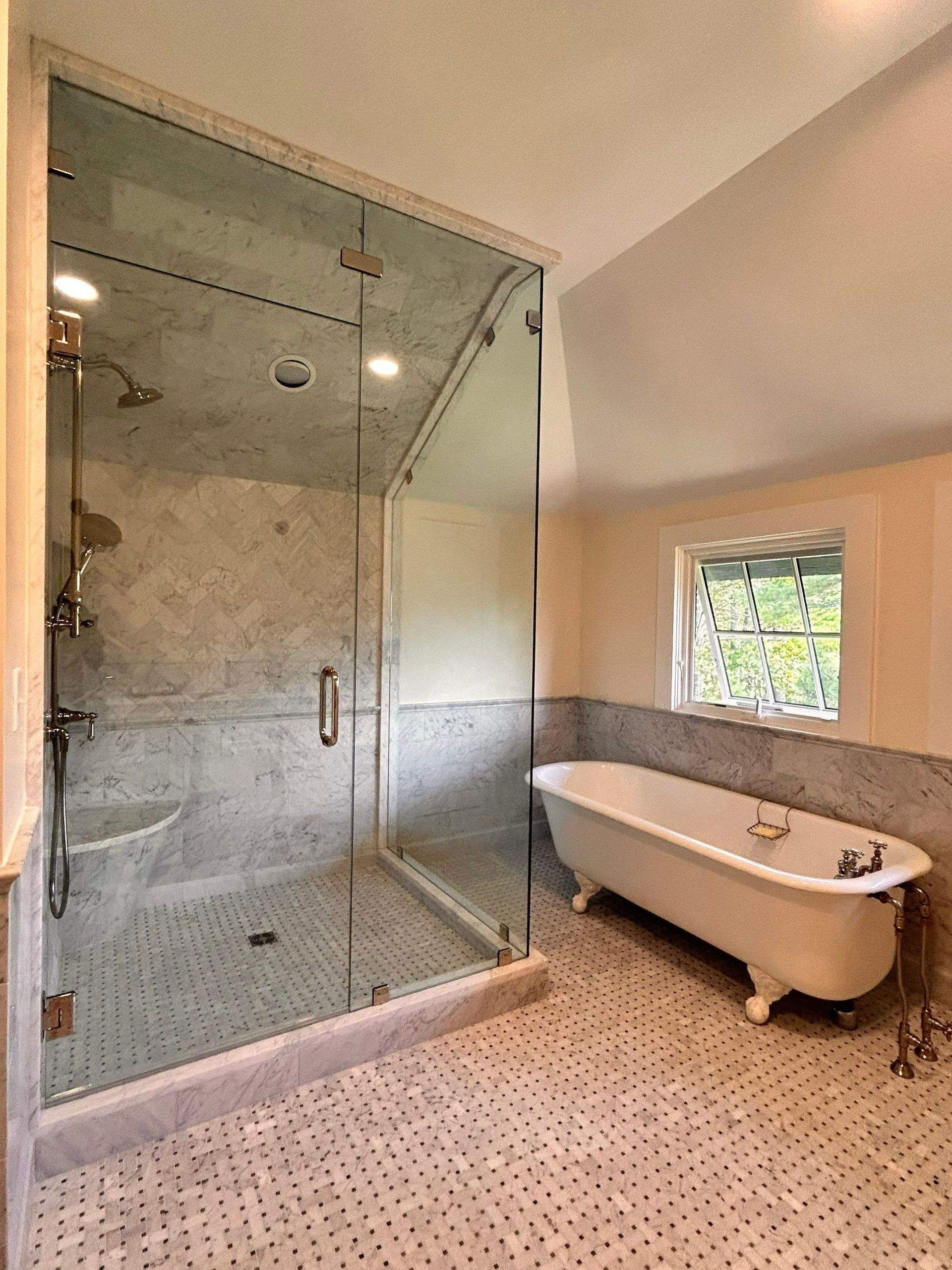 Modern bathroom with glass shower, freestanding tub, and patterned tile floor.