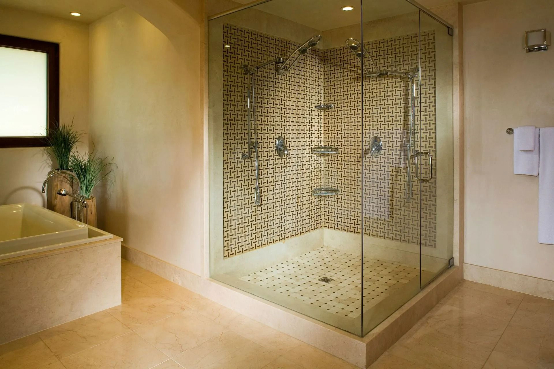 Spa shower room with glass-enclosed tiled shower and beige stone walls and floor