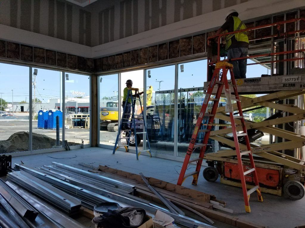 Construction workers on ladders in a glass-walled building under construction