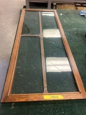 Wood-framed window pane with cracked glass leaning on a green surface