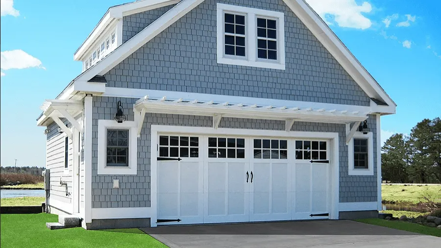 Gray two-story garage with white trim and double doors under a blue sky