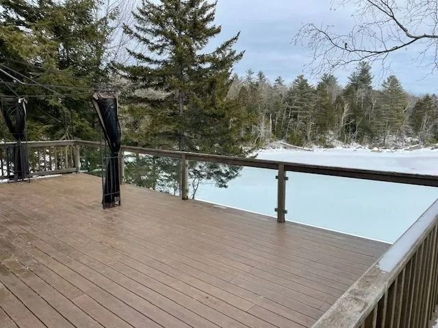 Wooden deck overlooking a frozen lake, surrounded by evergreen trees and winter landscape