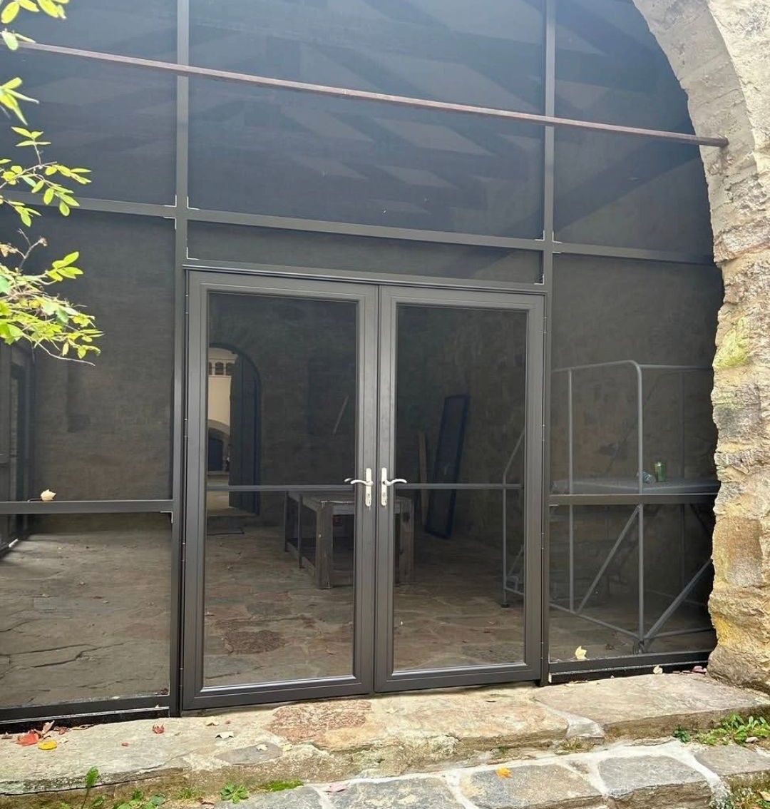 Glass double doors under a stone archway, reflecting the courtyard outside