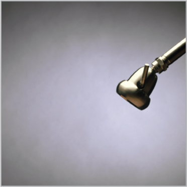 Metal showerhead spraying no water against a gray background
