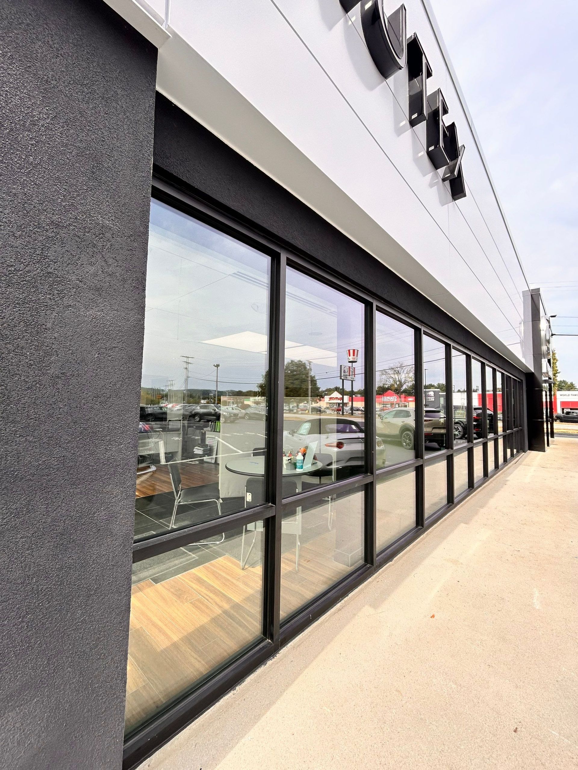 Storefront with black-framed windows along a sidewalk on a cloudy day