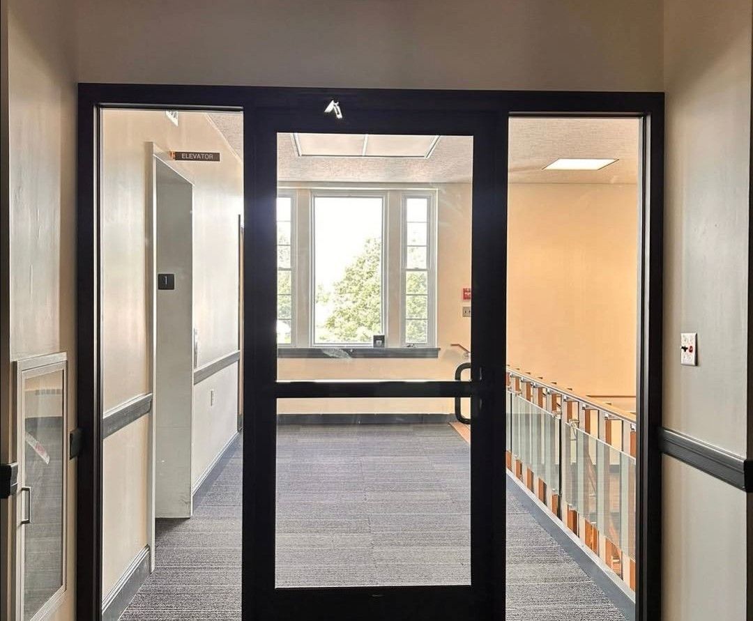 Hallway with glass double doors opening to a bright office or classroom area