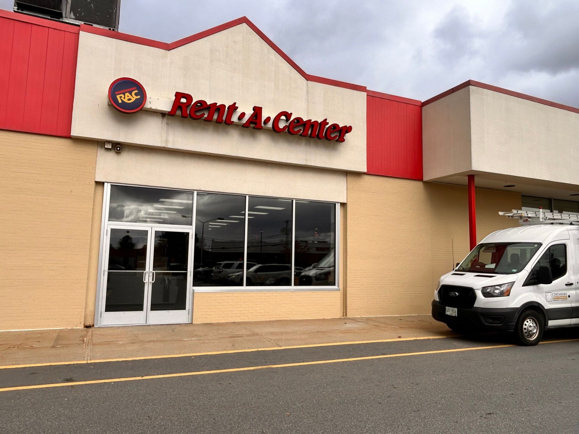Retail store exterior with red signage and a white van parked outside