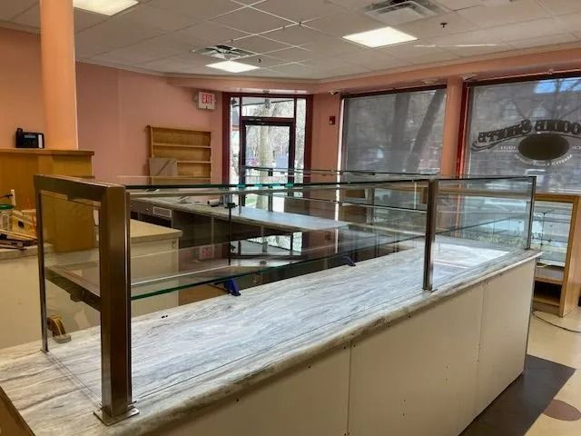 Empty café counter with glass display cases and white cabinets in a pink-walled interior