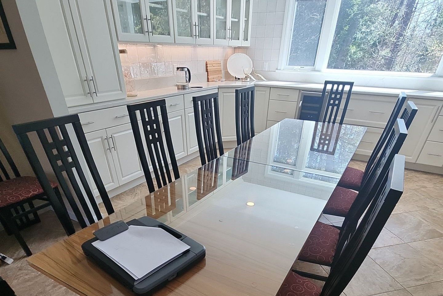Dining table with black chairs in a bright kitchen beside large windows
