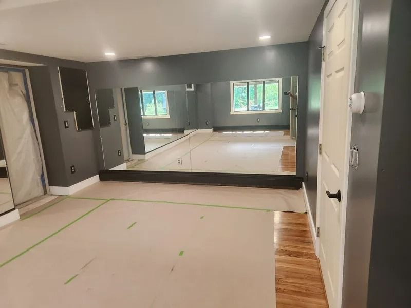 Unfinished living room with gray walls, taped floor, mirrored wall, and wood flooring along one side