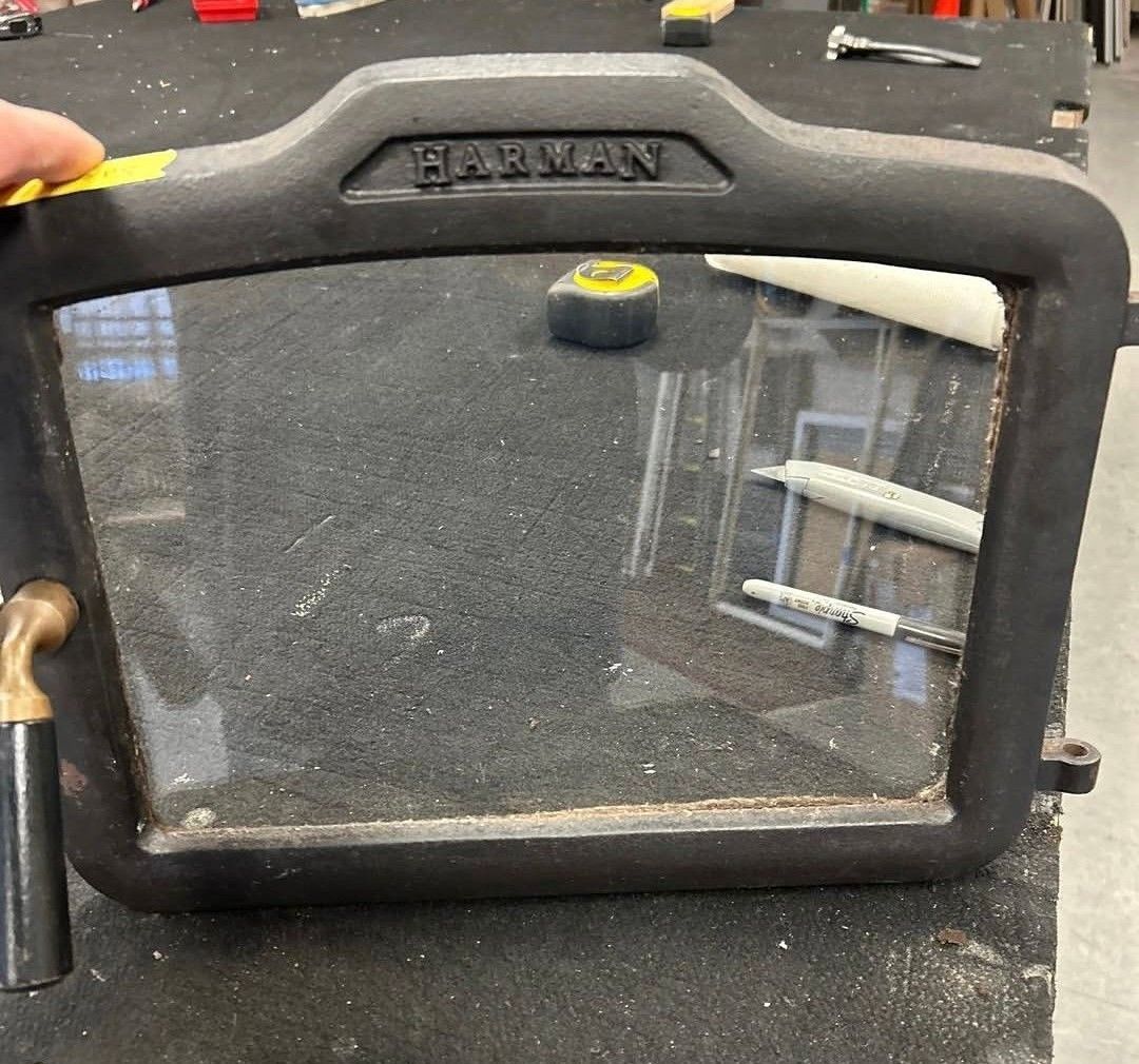 Black Garmin device with a clear front panel resting on a workbench, with tools visible in the background