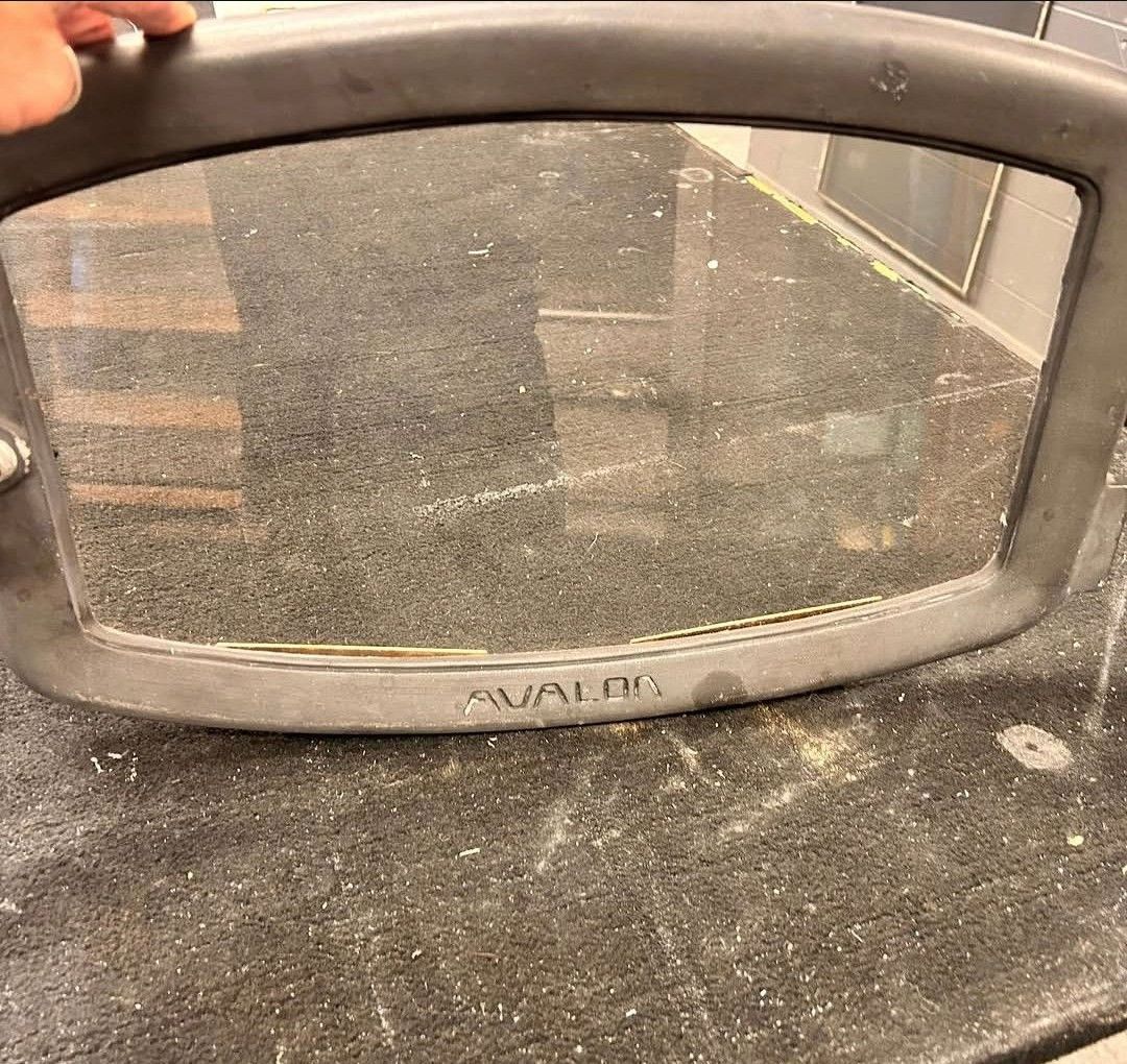 Dusty handheld mirror on a countertop, reflecting a dark room.