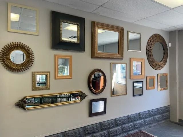 Wall with a gallery of assorted framed mirrors and pictures in a hallway