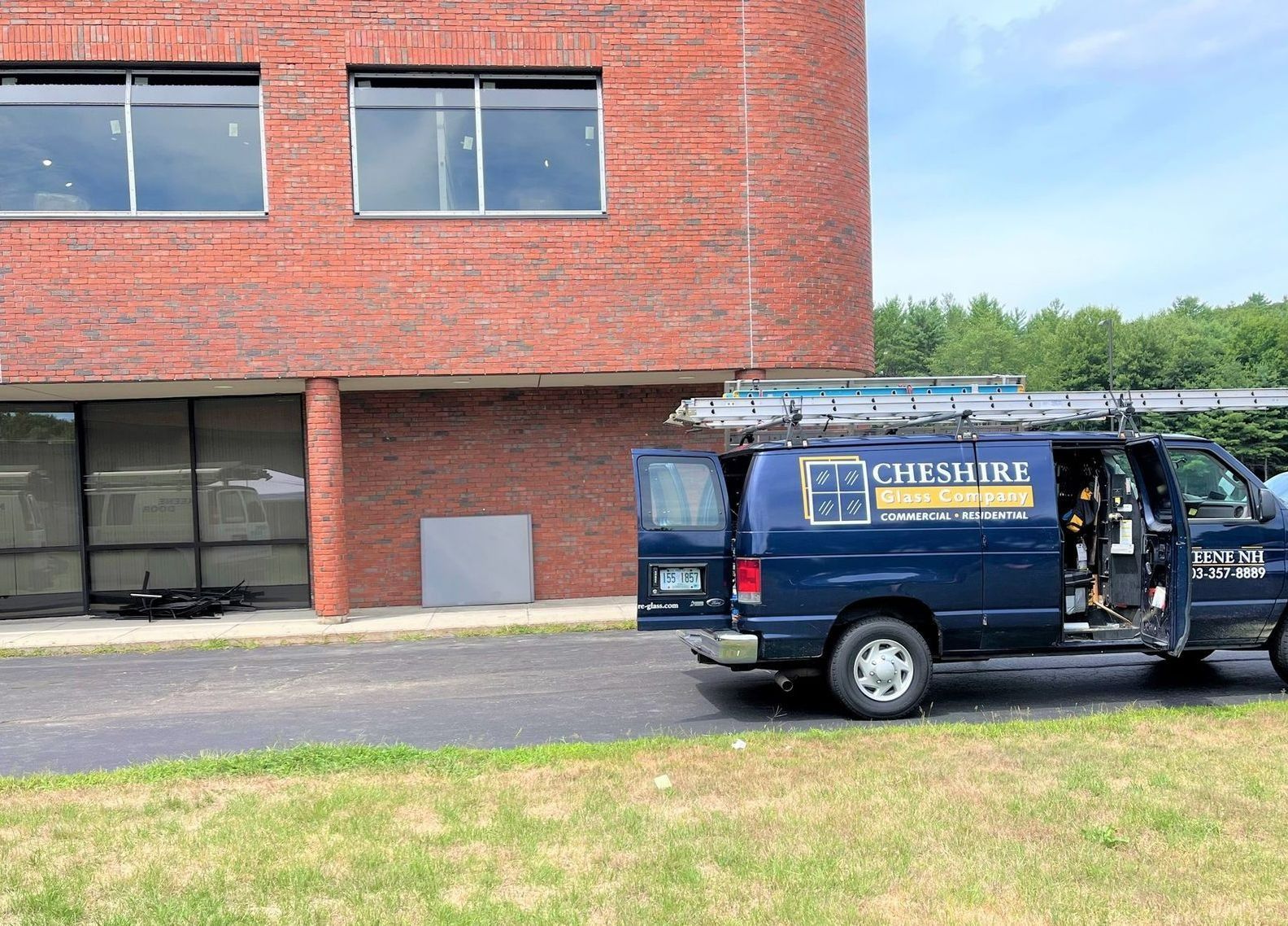 Blue service van parked by a red brick building with an open side door.