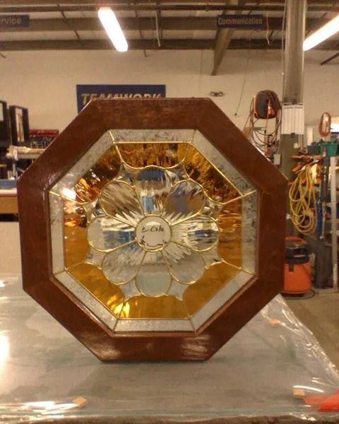 Octagonal wooden-framed stained-glass window with blue and amber floral design, in a workshop