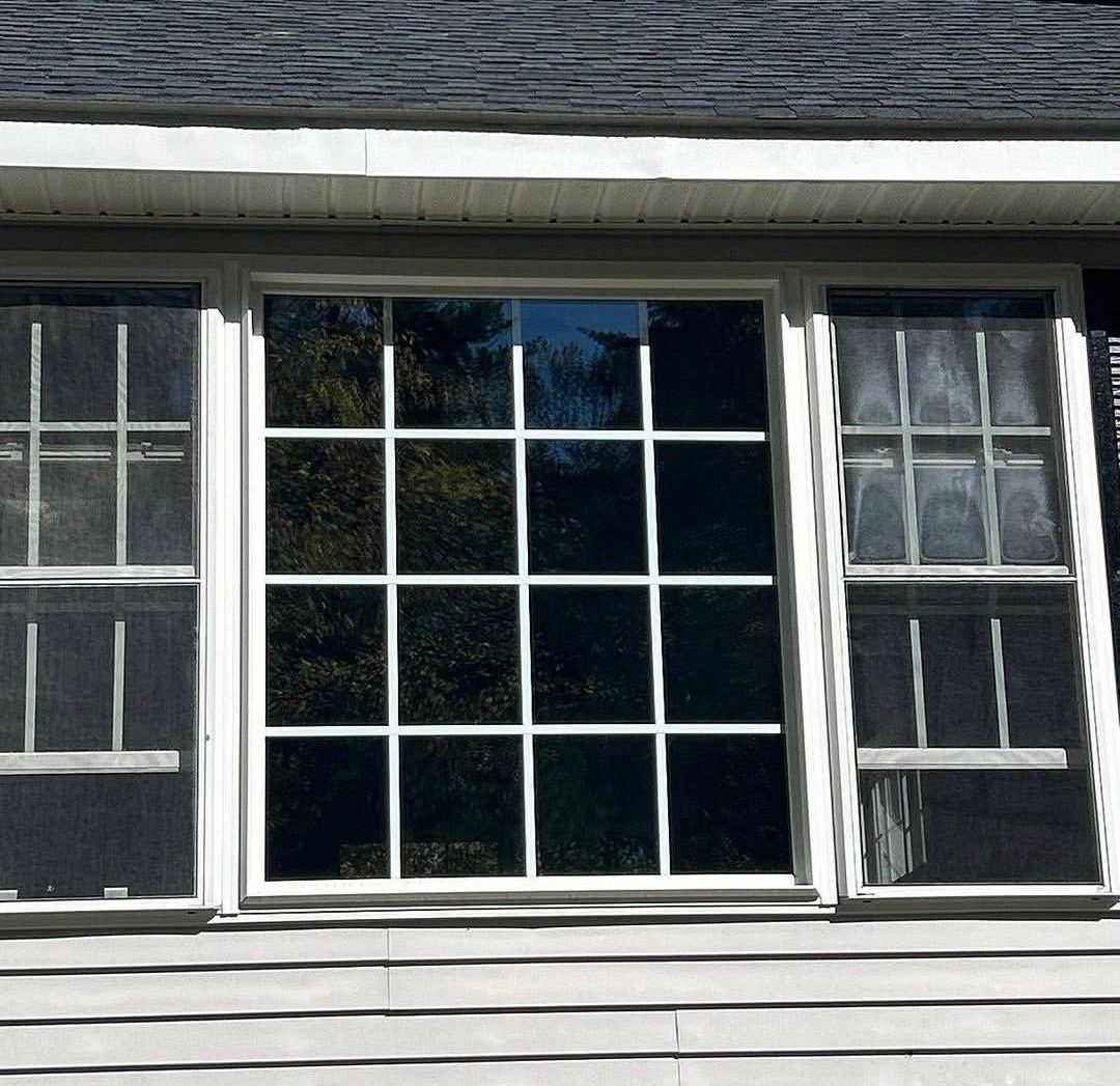Three-pane house window with white grid panes and dark wood siding
