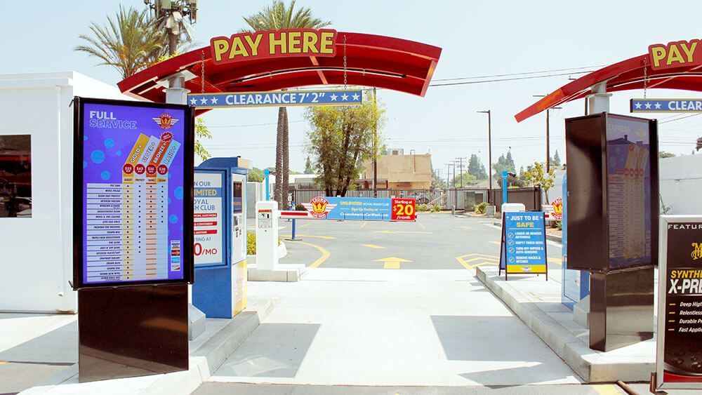 A pay here sign is above the entrance to a car wash