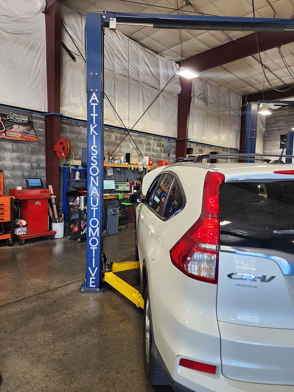 A white car is sitting on a lift in a garage.