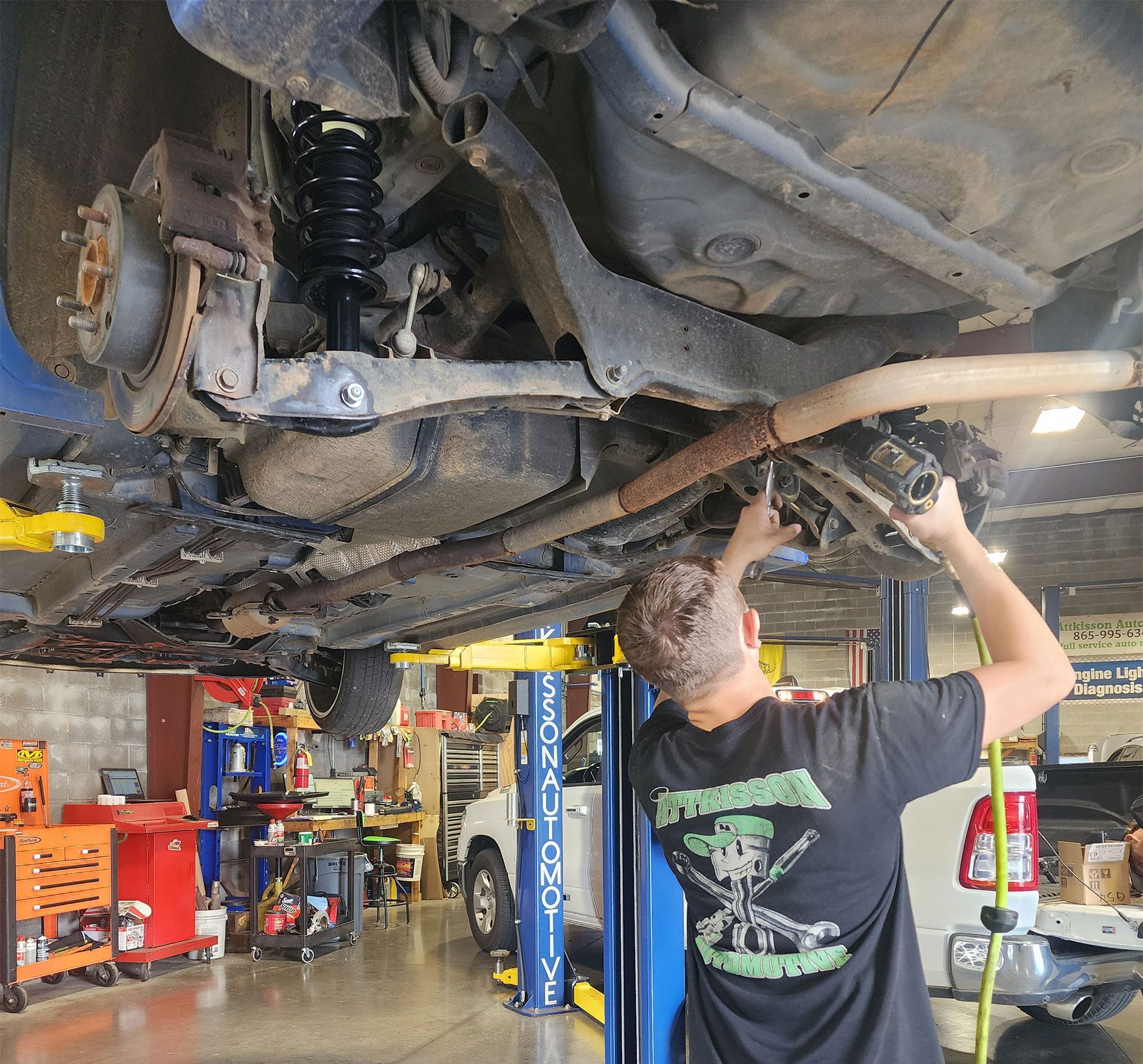 A man in a black shirt is working under a car