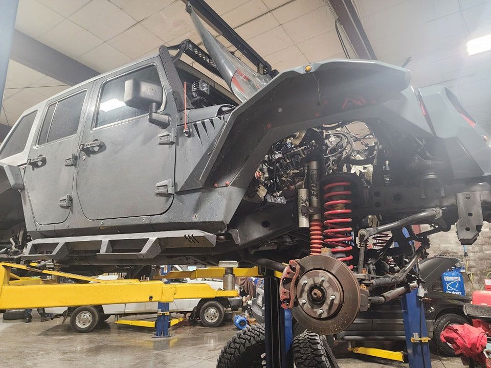 A jeep is sitting on a lift in a garage.