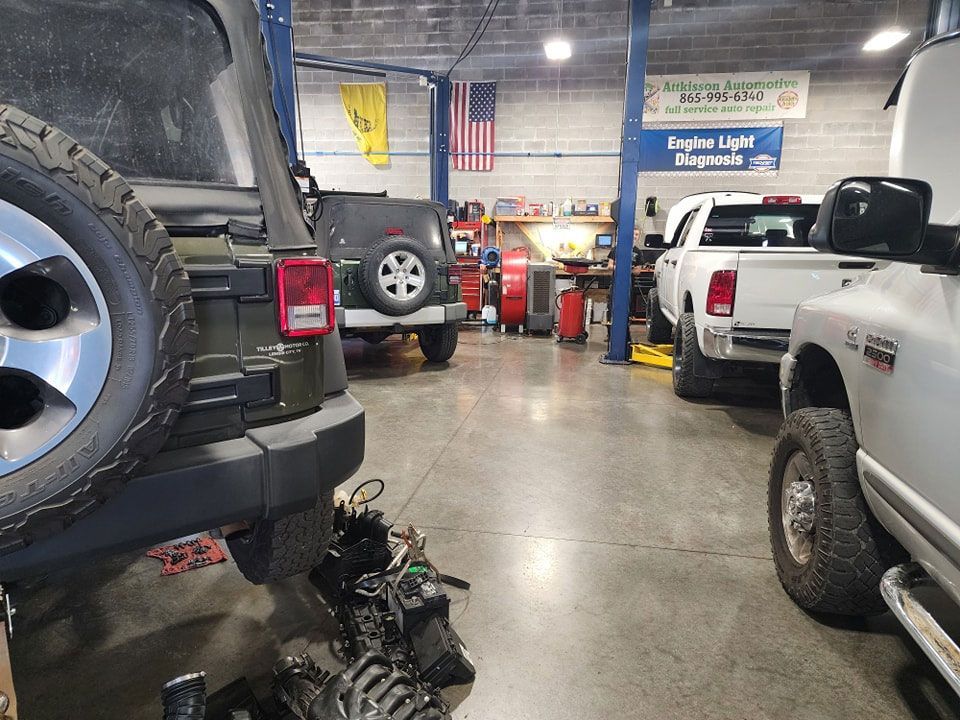 A jeep and a truck are parked in a garage.