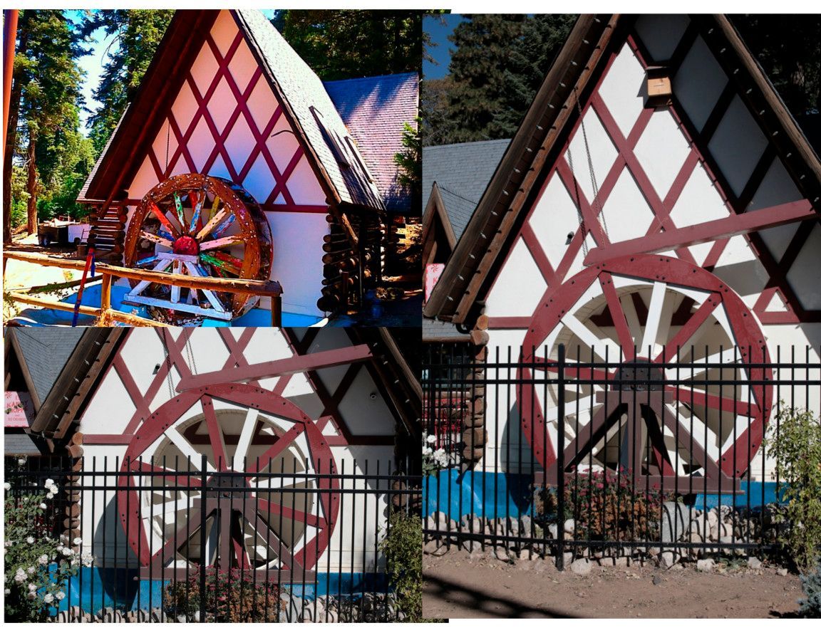 Water mill with red and white timber frame, water wheel, and dark fence.