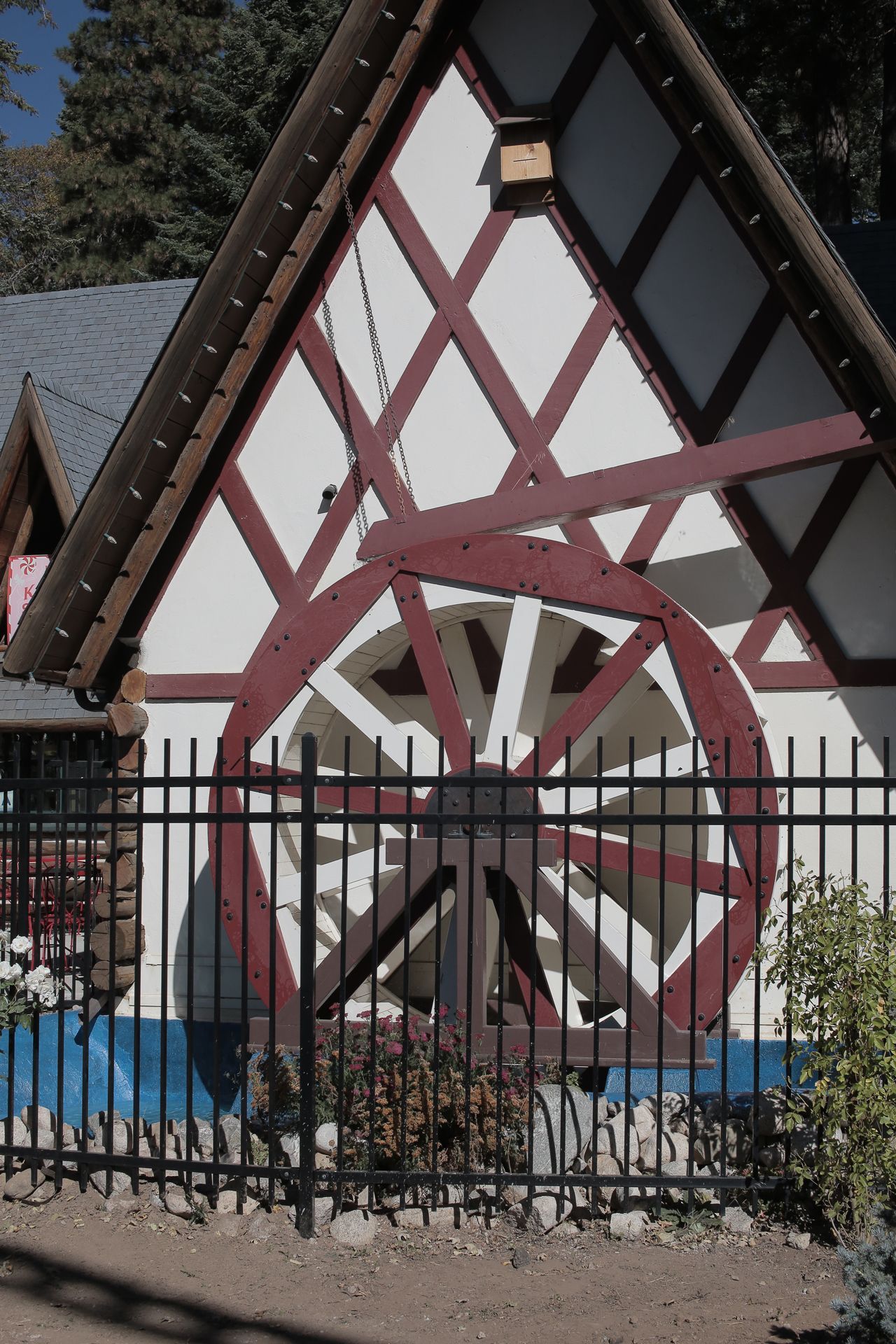 Building with a decorative water wheel, black fence, and Tudor-style detailing.