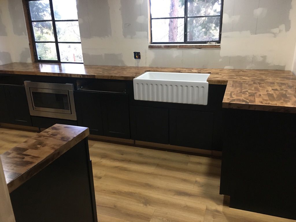 Kitchen remodel: Black cabinets, copper countertops, white farmhouse sink, and windows.