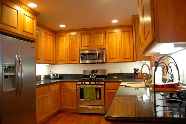 Kitchen with light brown cabinets, stainless steel appliances, and dark countertops.
