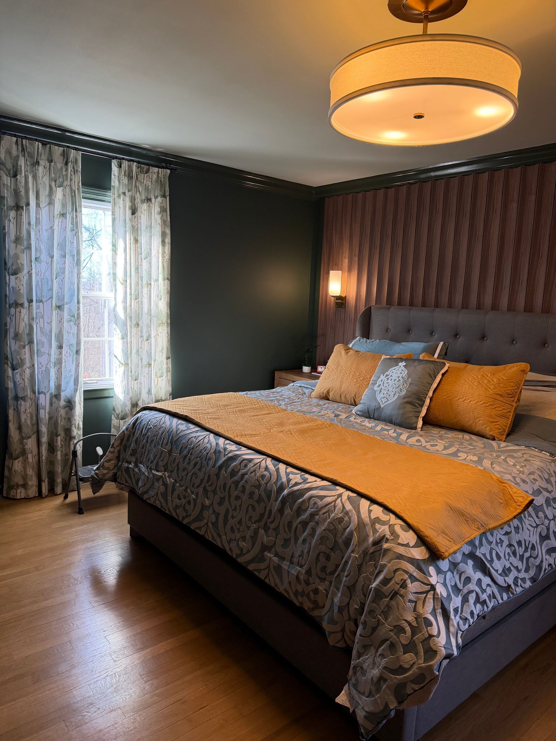 Cozy bedroom with a tufted bed, patterned bedding, and soft curtains by a bright window