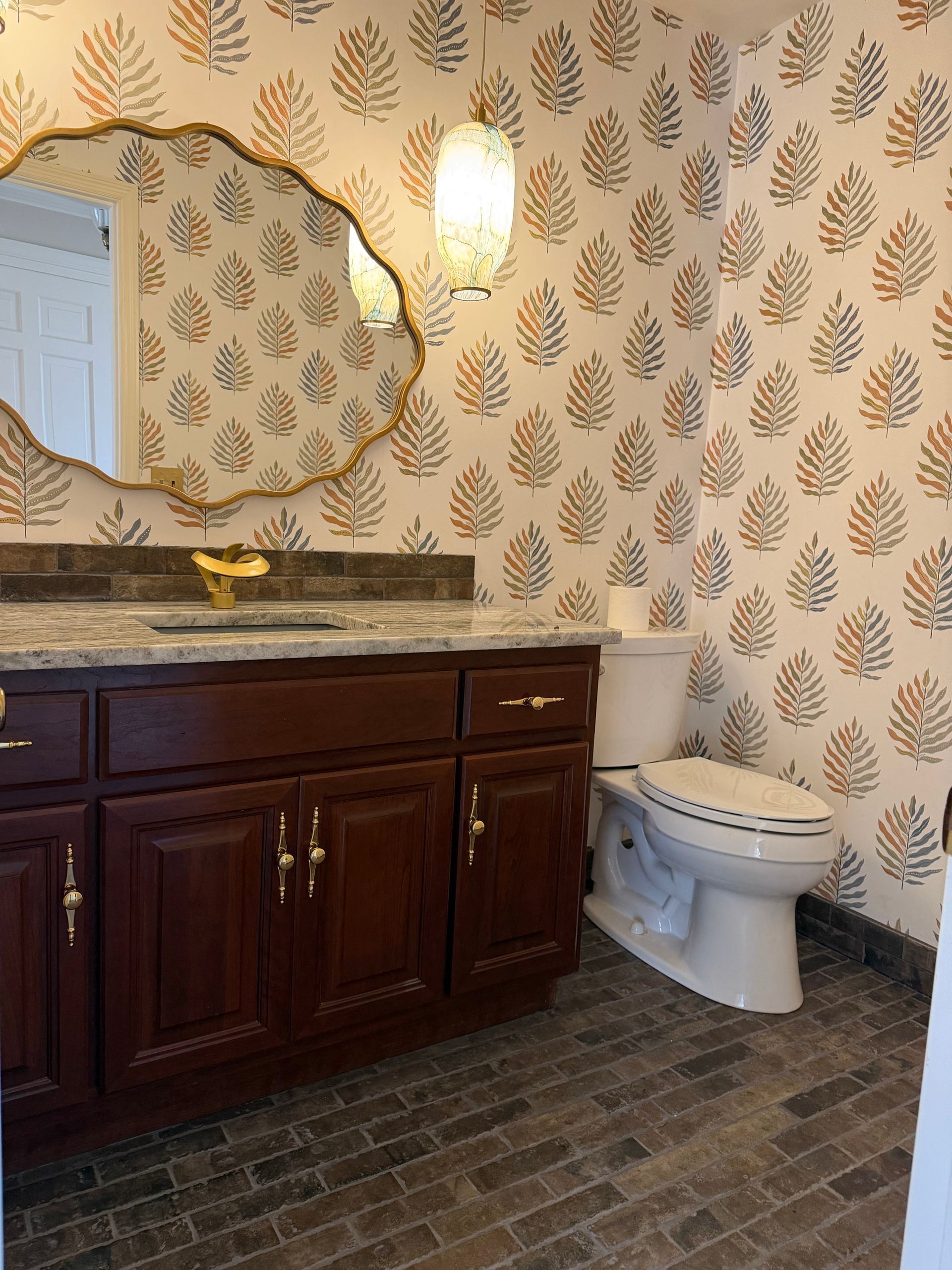 Bathroom with dark wood vanity, patterned wallpaper, large mirror, and white toilet on dark tile floor