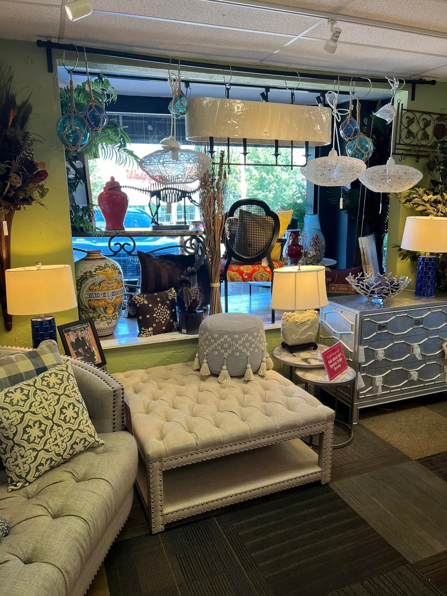Eclectic living room with tufted ottoman, patterned sofas, lamps, plants, and a bright window display