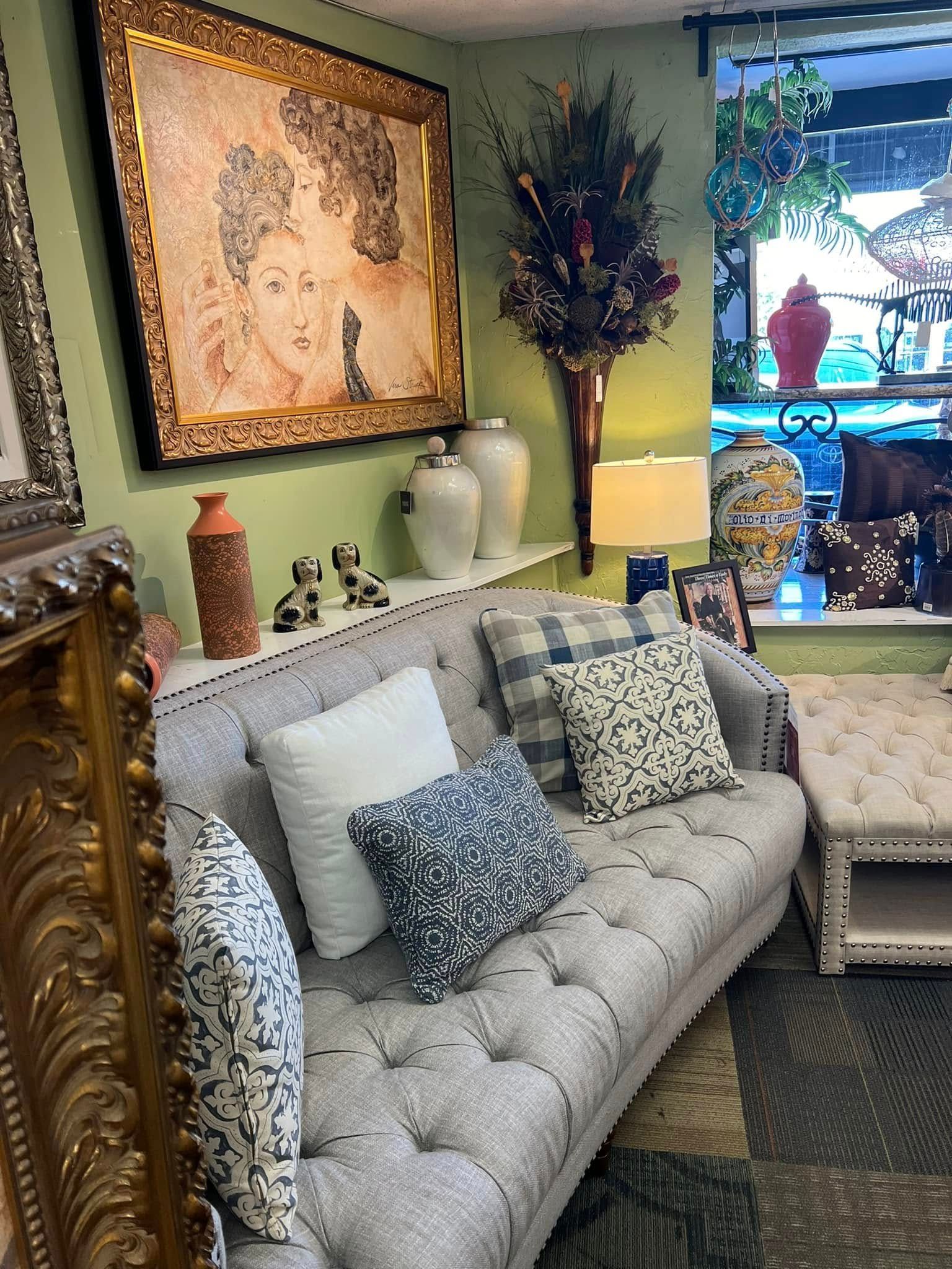 Elegant living room with gray tufted sofa, patterned pillows, green walls, and a large framed portrait above.