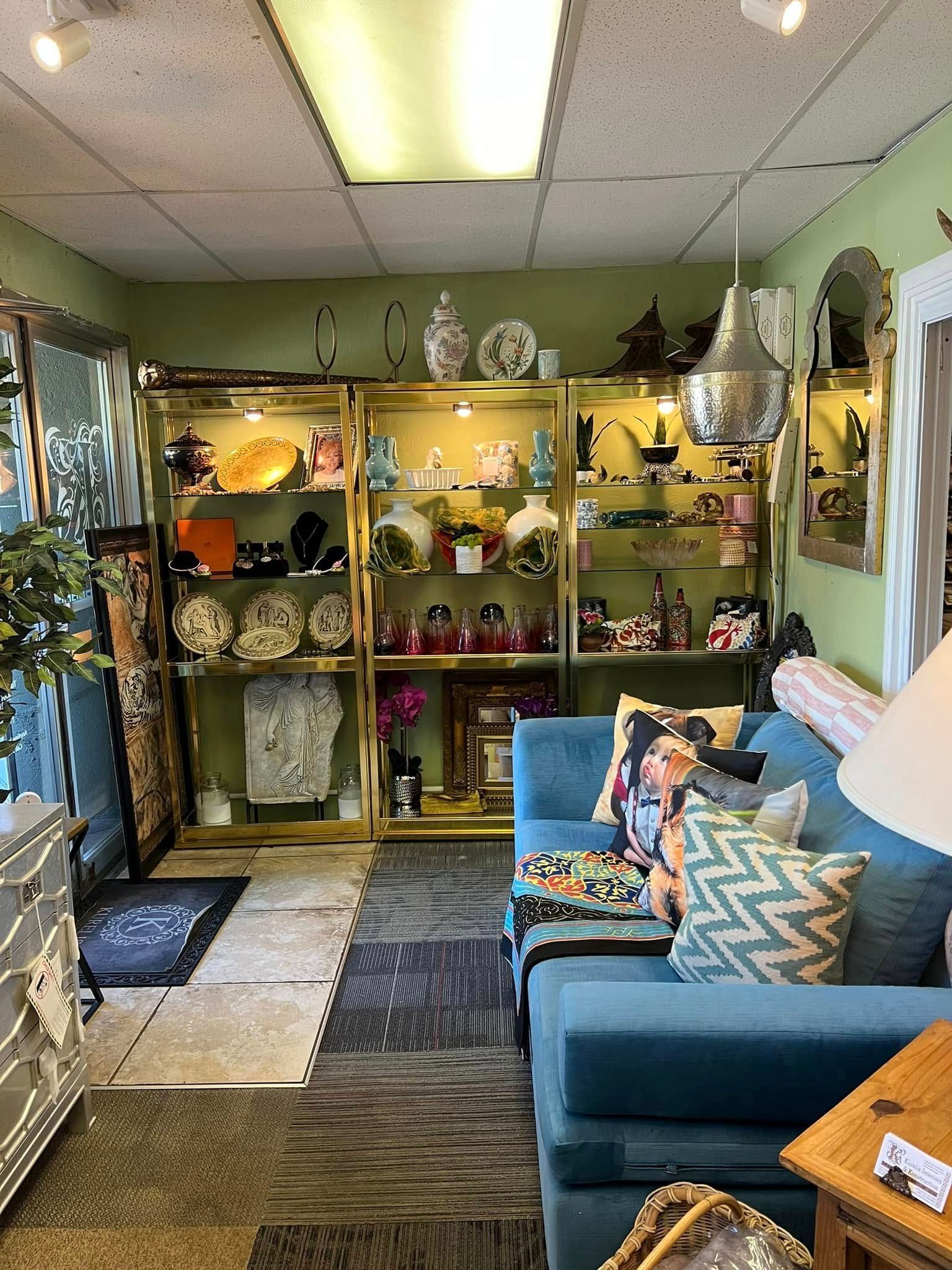 Curio shop interior with shelves of decor, blue couch, patterned rug, and overhead fluorescent lights