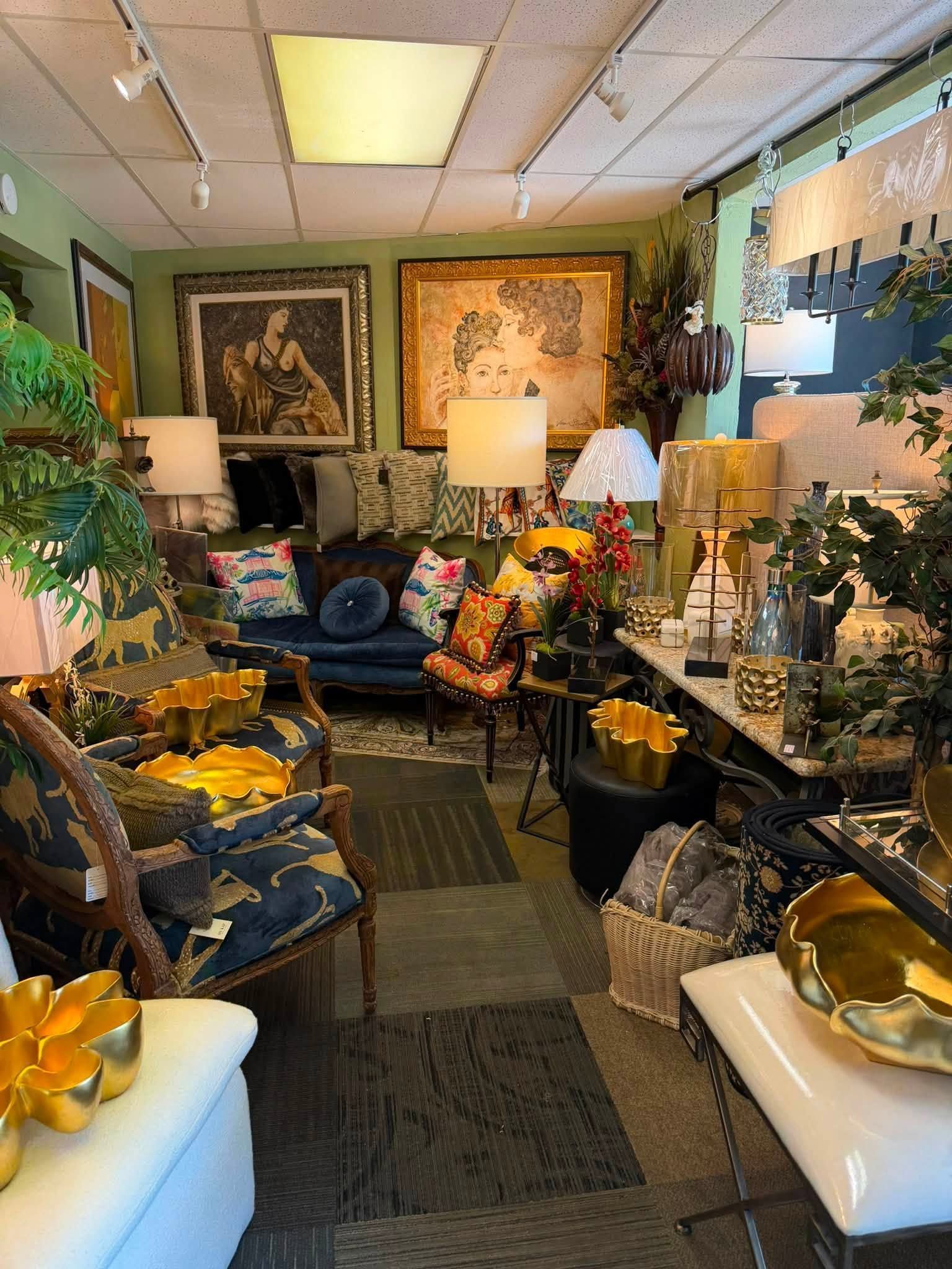 Cluttered floral-filled room with lamps, framed art, and white ottomans in a cozy, vintage-style interior