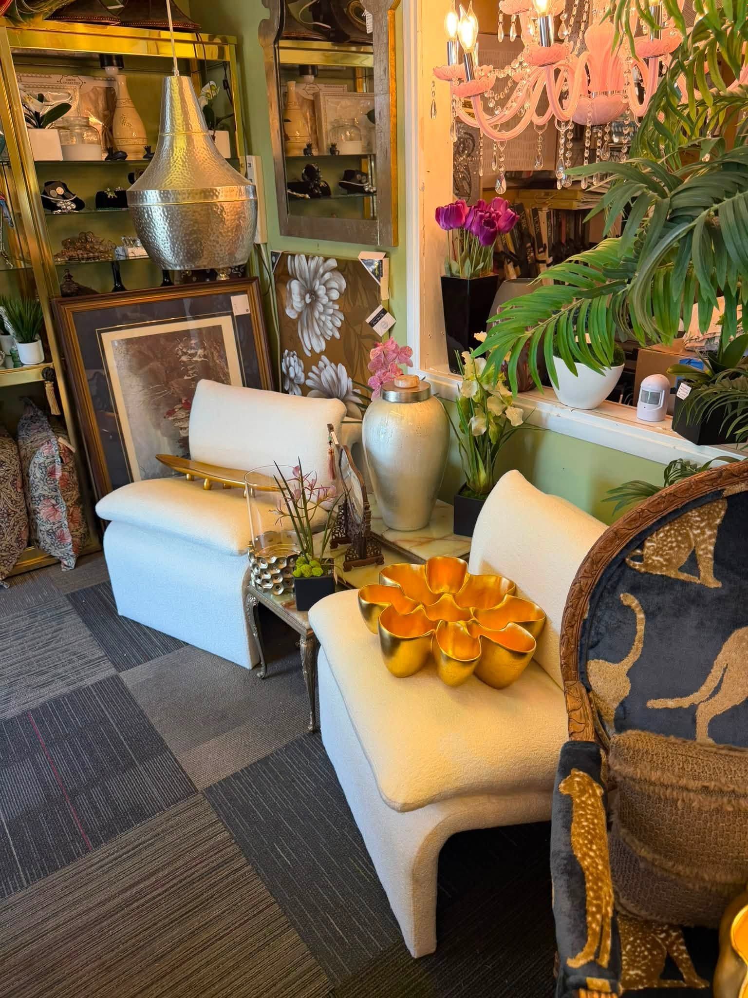Elegant shop display with cream chairs, gold accents, decorative vases, and patterned rugs in a cozy interior.