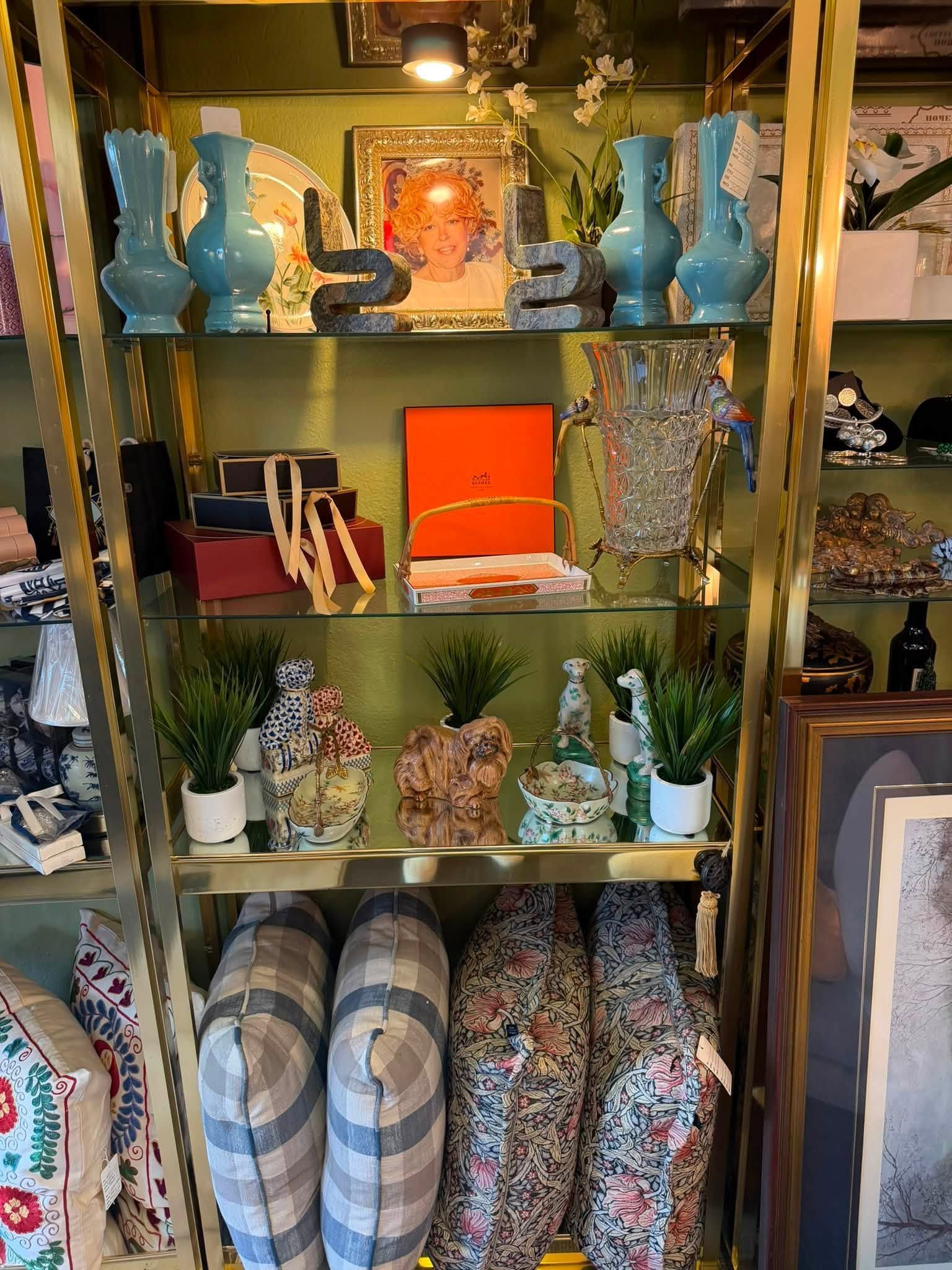 Colorful display shelf with vases, floral decor, baskets, and patterned cushions in a shop interior