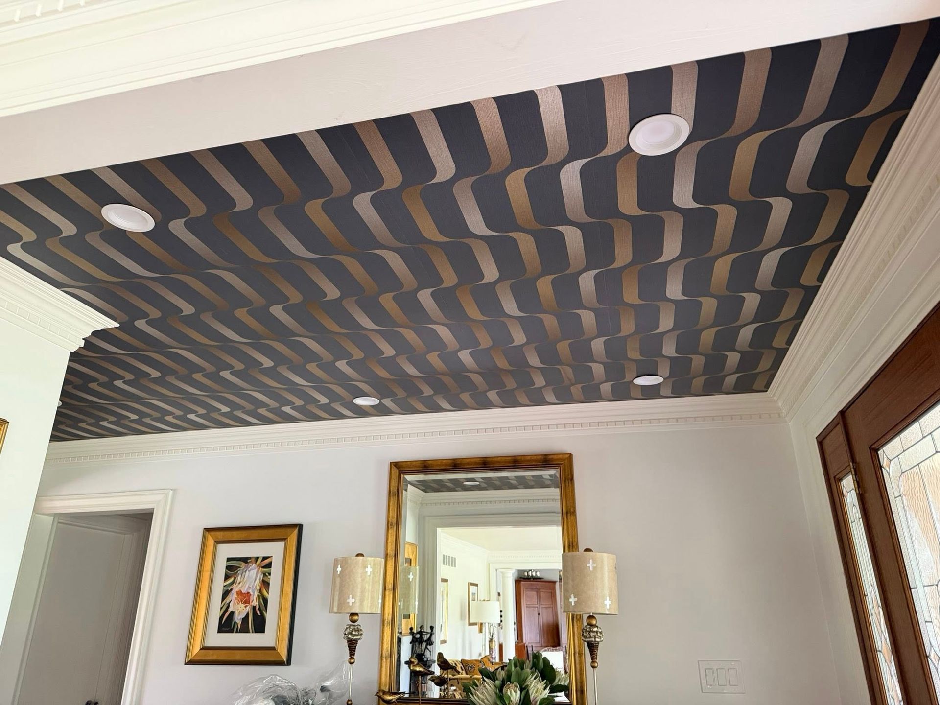 Living room with a striped dark ceiling, white walls, mirror, framed art, and wall sconces