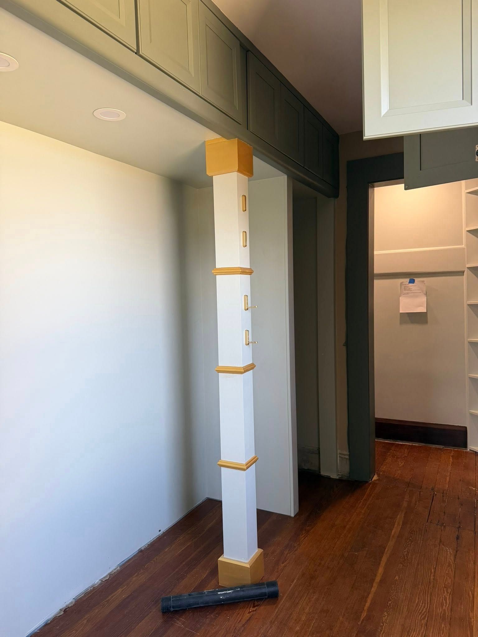Wrapped white column in a hallway with dark wood floor and ceiling beam